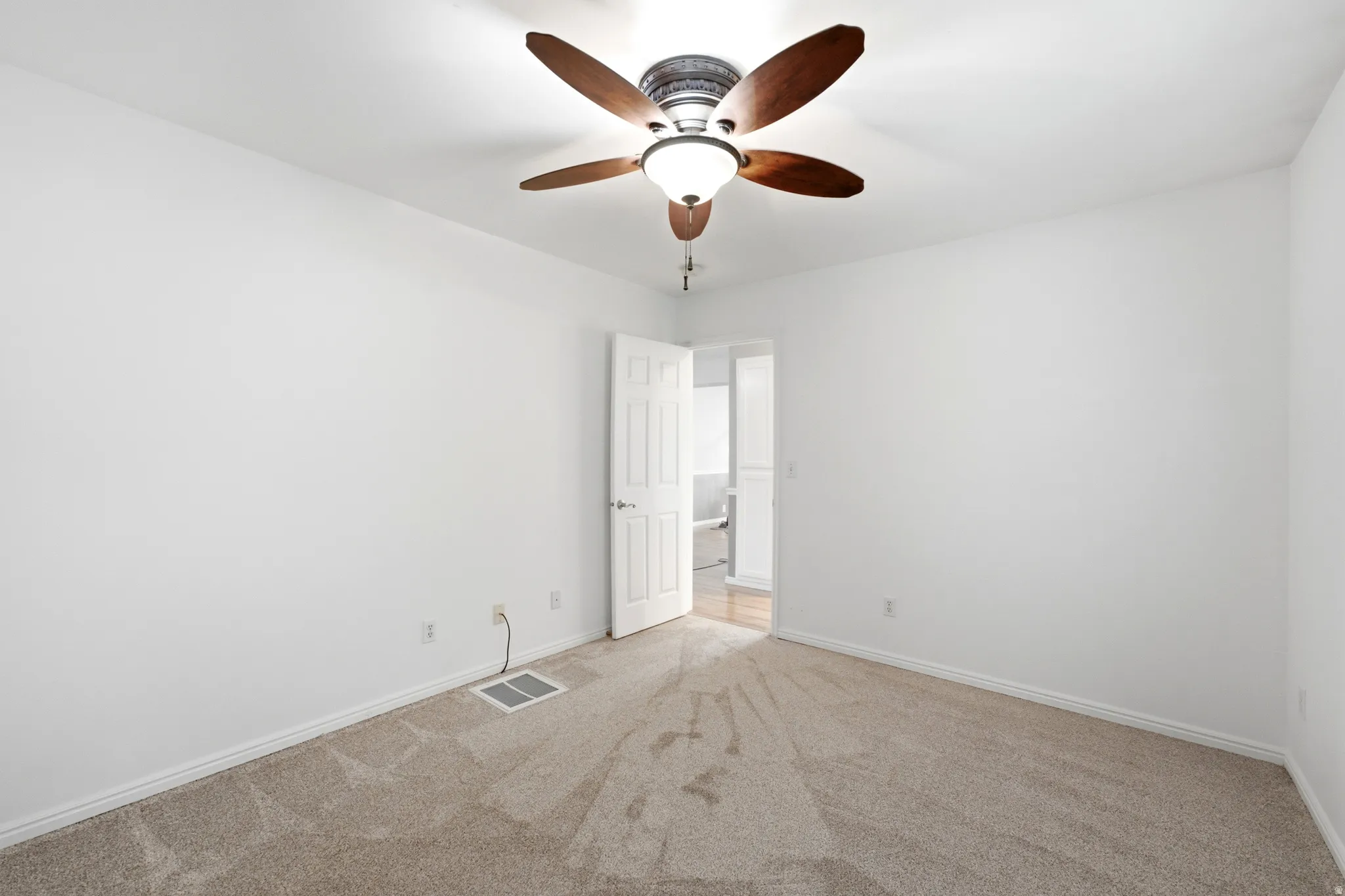 Neutral wall finishes, carpet flooring, and a ceiling fan with integrated lighting