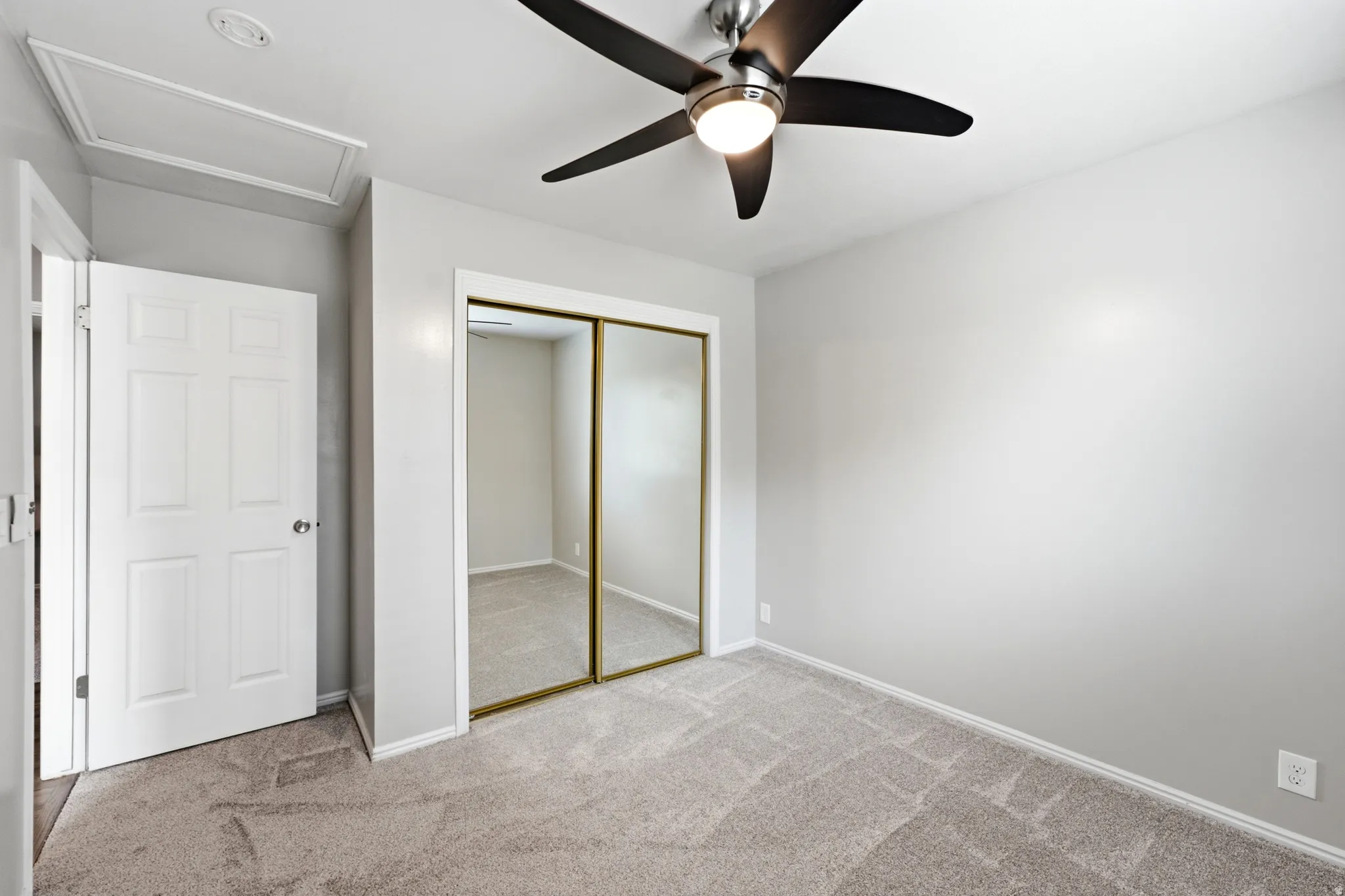 Recessed ceiling panel, paneled door, mirrored closet doors, ceiling fan with integrated lighting, and carpeted flooring