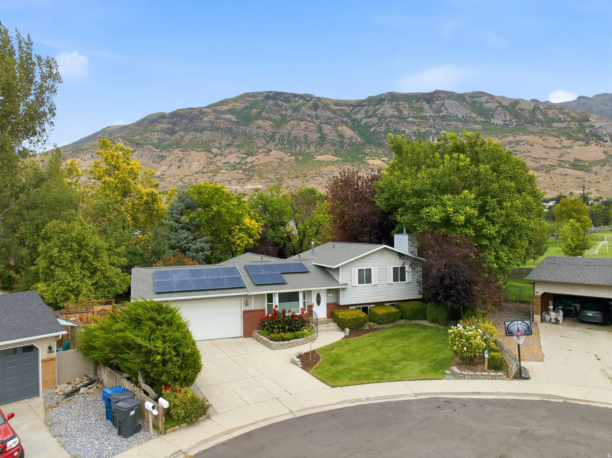 Split-level residence featuring solar panels, an attached two-car garage, and a detached carport