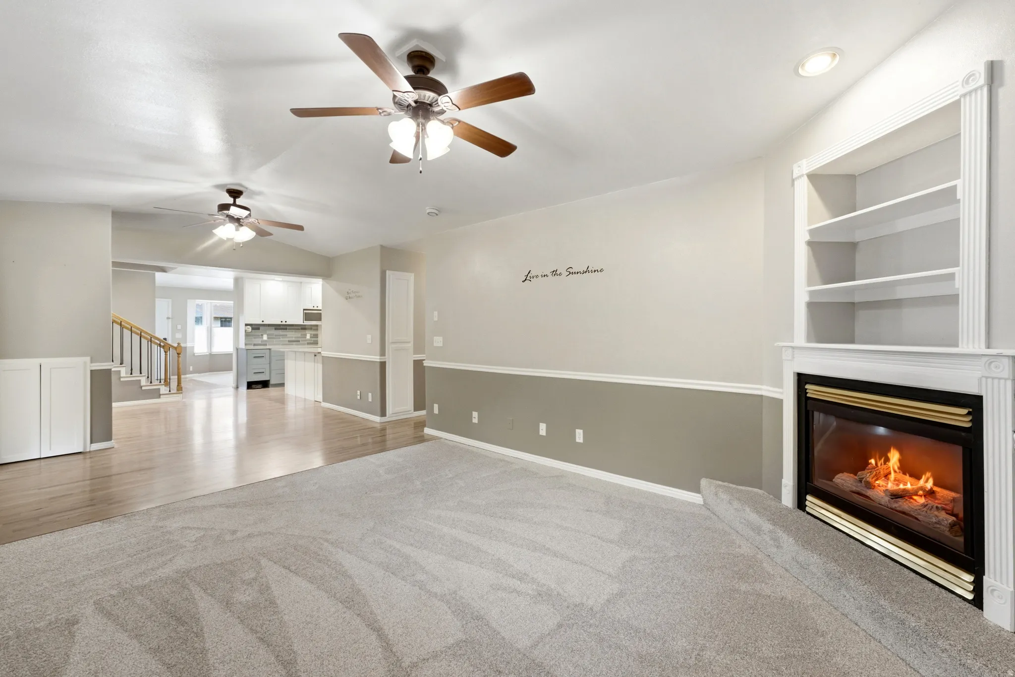 Vaulted ceiling, two ceiling fans, built-in shelving, fireplace with mantel, and wood-finish flooring
