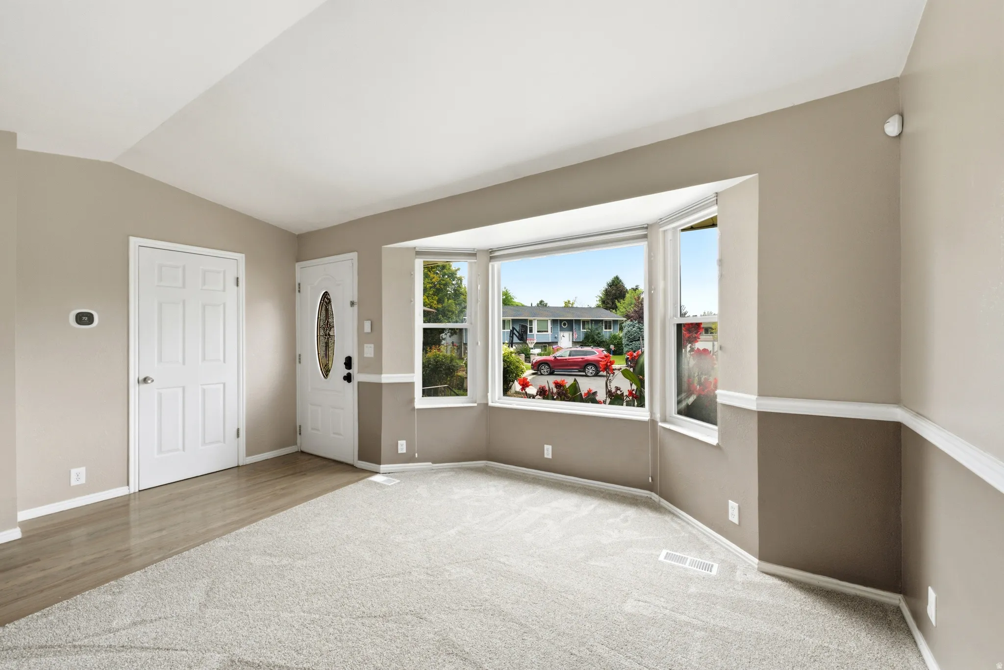 Recessed bay window, two-tone wall paint, white trim, wood-finish flooring, and light-toned carpeting