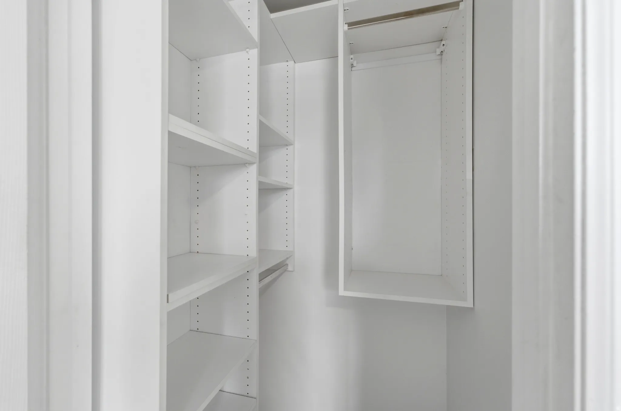 Built-in white shelving system featuring adjustable shelves and a hanging rod