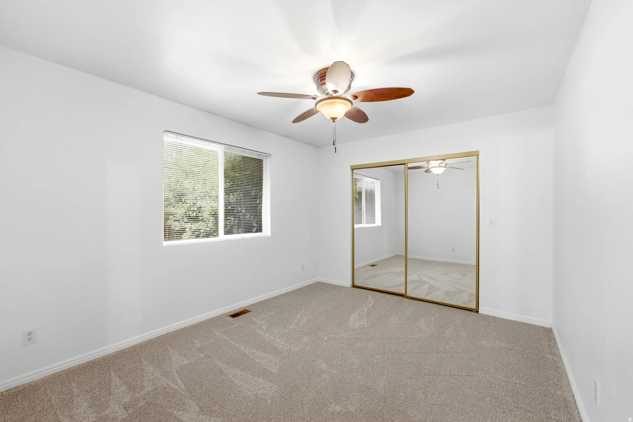 Recessed lighting with a ceiling fan, mirrored closet doors, and neutral carpeting