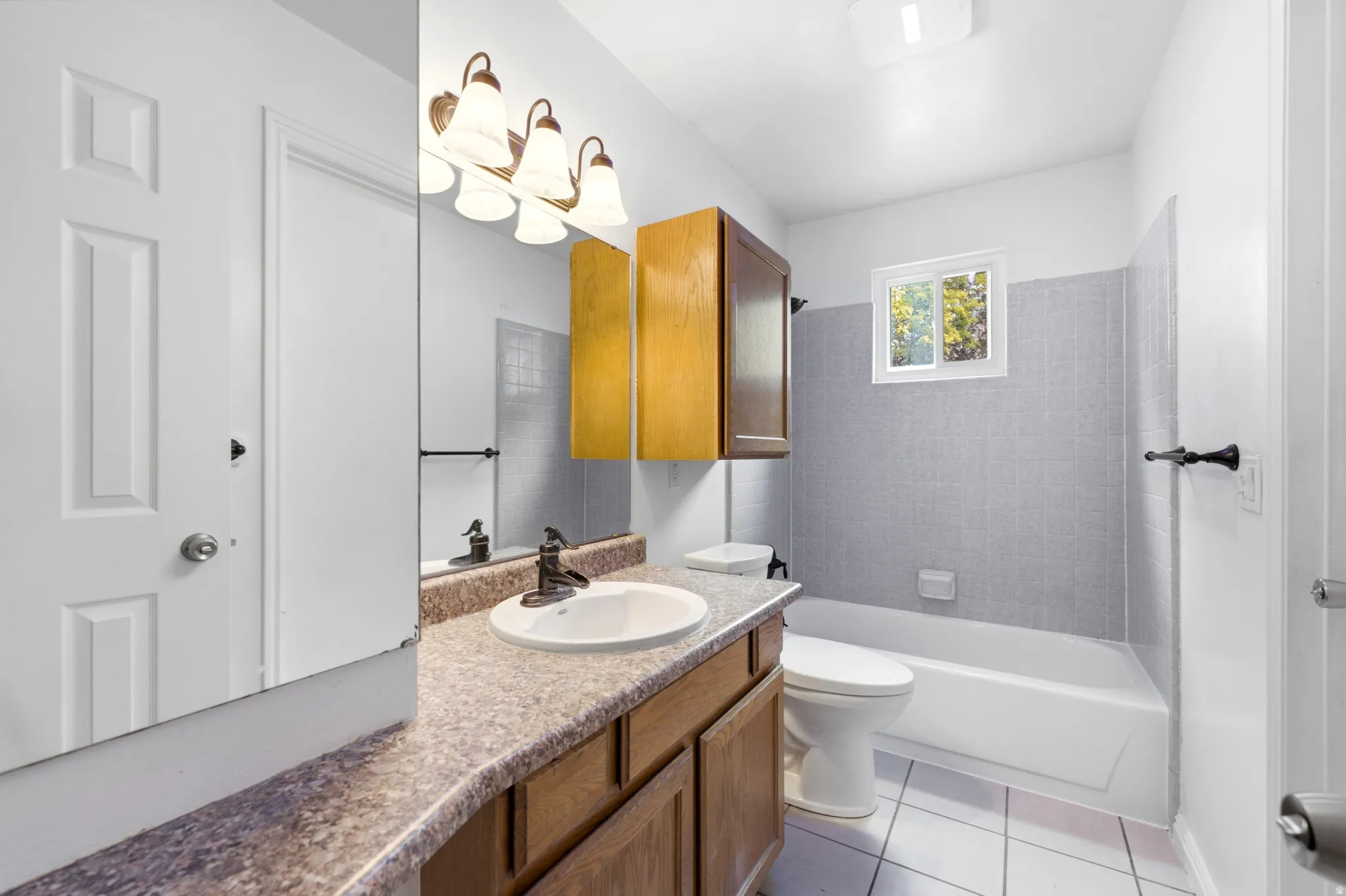 Vanity with an integrated sink, wood-finish cabinetry, and a bronze-finish light fixture