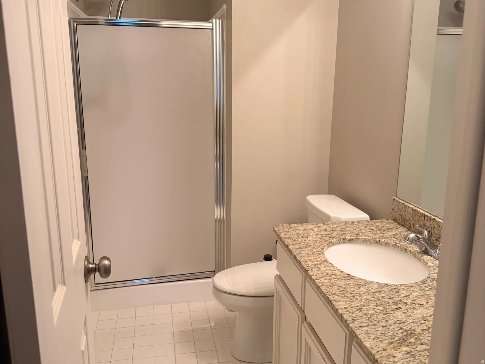 2nd Bathroom featuring a shower with a sliding glass door, white tile flooring, a white vanity with a granite-style countertop, and a built-in mirror