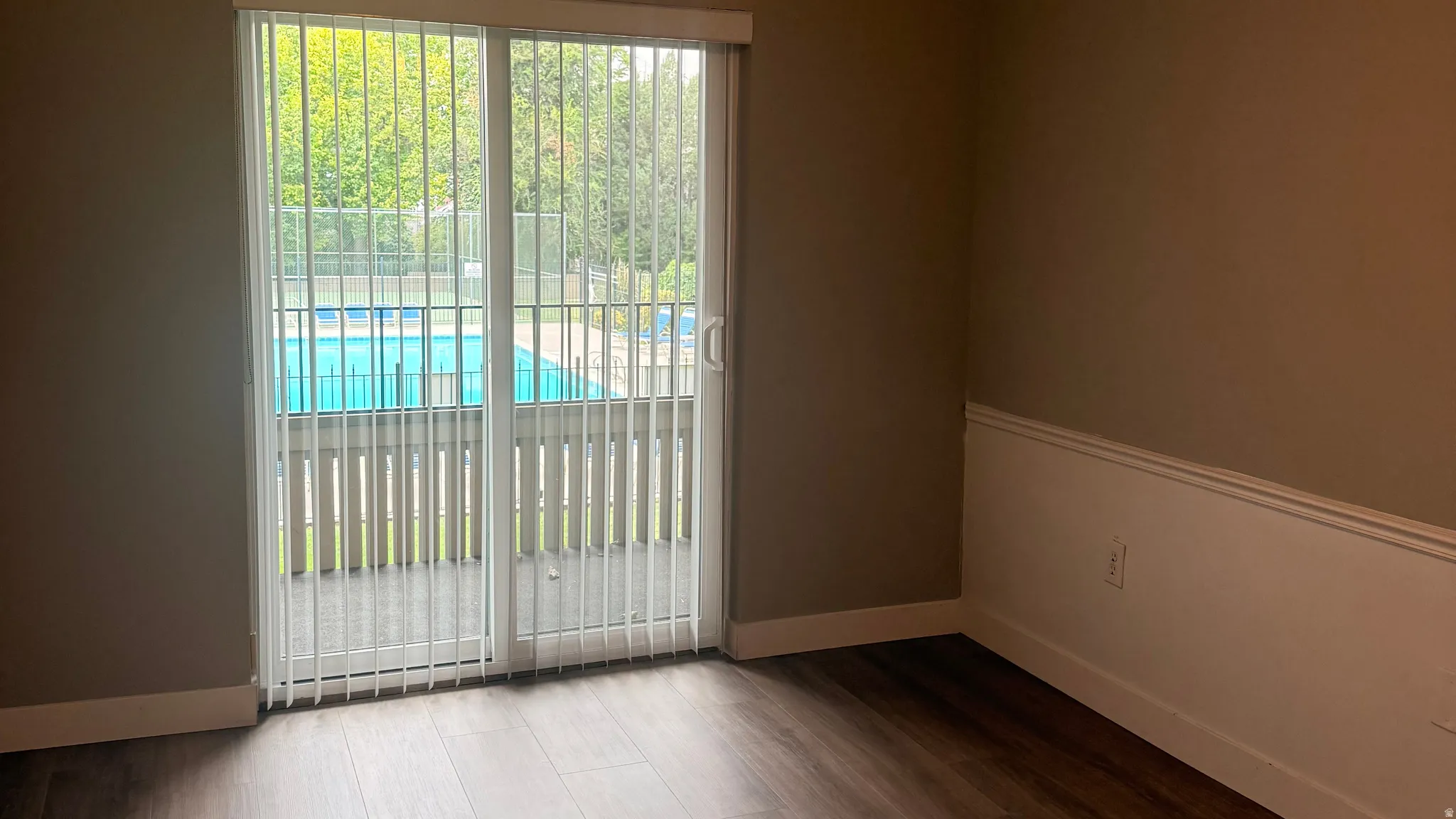 Main Bedroom with balcony door...Sliding glass door leading to a private outdoor space, wood-finish flooring, wainscoting, and a full-size pool