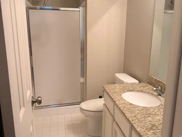 2nd Bathroom featuring a shower with a sliding glass door, white tile flooring, a white vanity with a granite-style countertop, and a built-in mirror