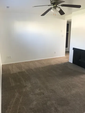 Neutral tone carpeting and white walls with a ceiling fan featuring integrated lighting