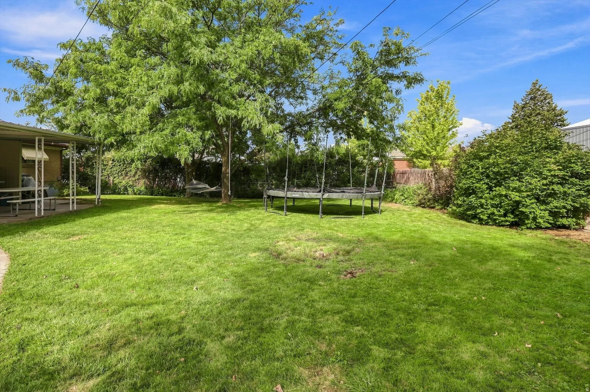 Expansive lawn with mature trees and a covered patio area