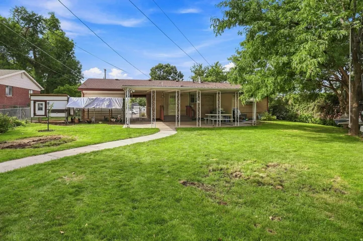 Expansive grassy lawn with a curved concrete pathway leading to a covered patio