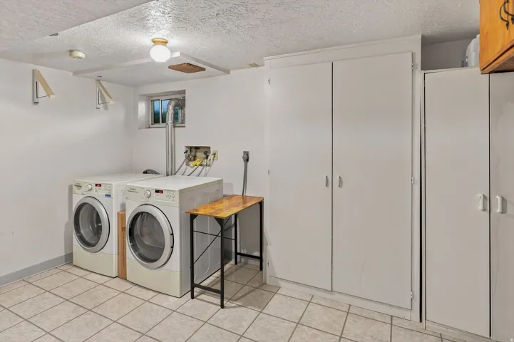 Laundry area featuring tile flooring and white cabinetry