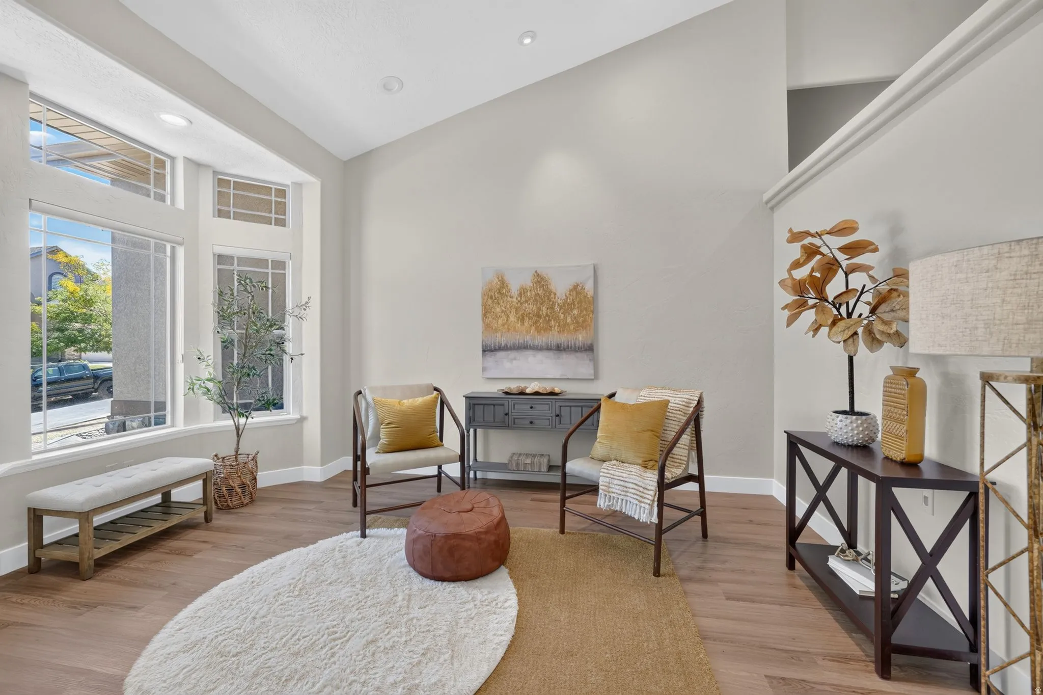 Bay window with upper transom windows, vaulted ceiling, recessed lighting, and wood-finish flooring