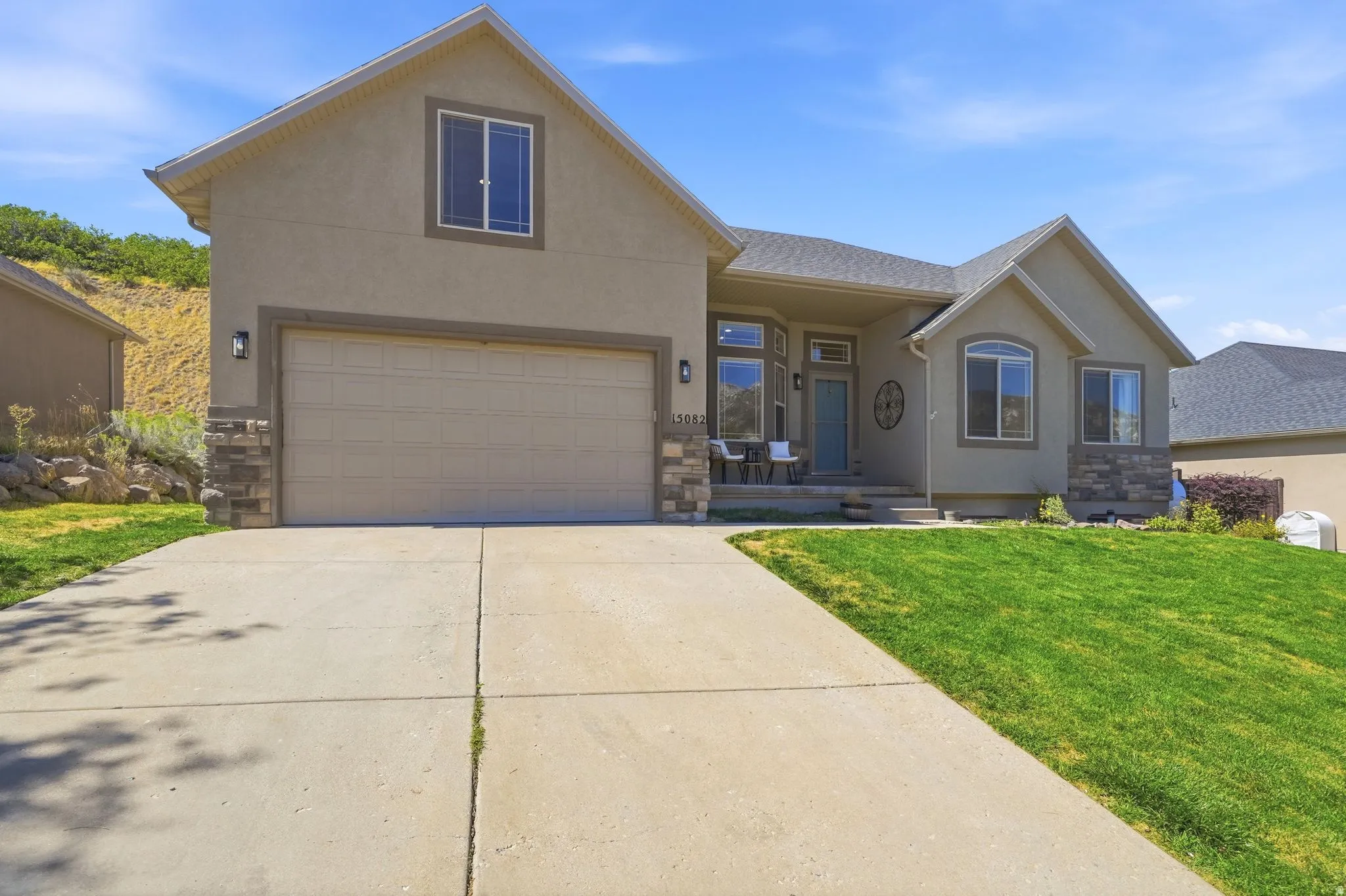 Contemporary stucco exterior featuring stone accents, a concrete driveway, and a covered front porch