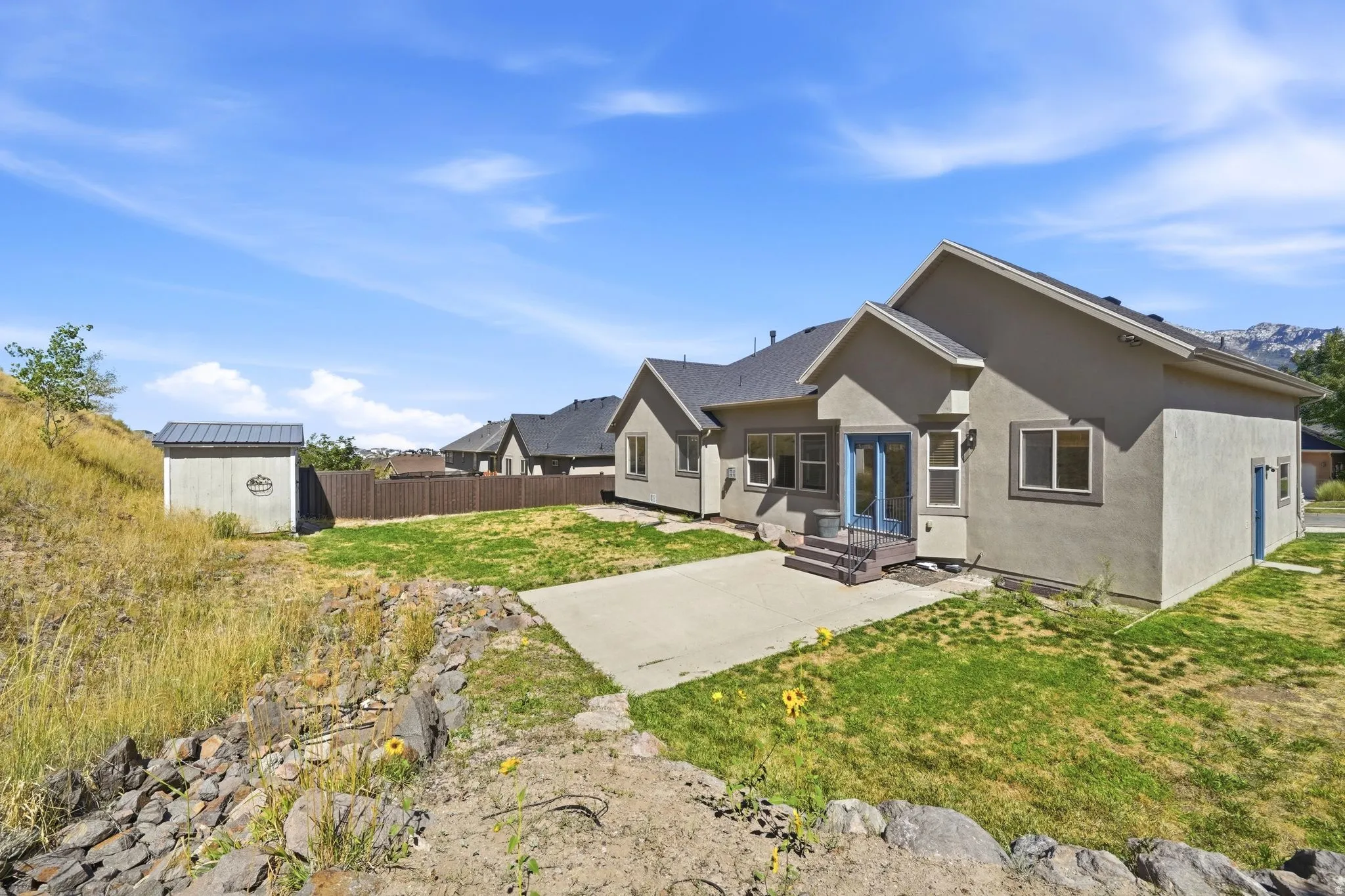 Rear exterior with a concrete patio, stucco siding, and a gabled roofline