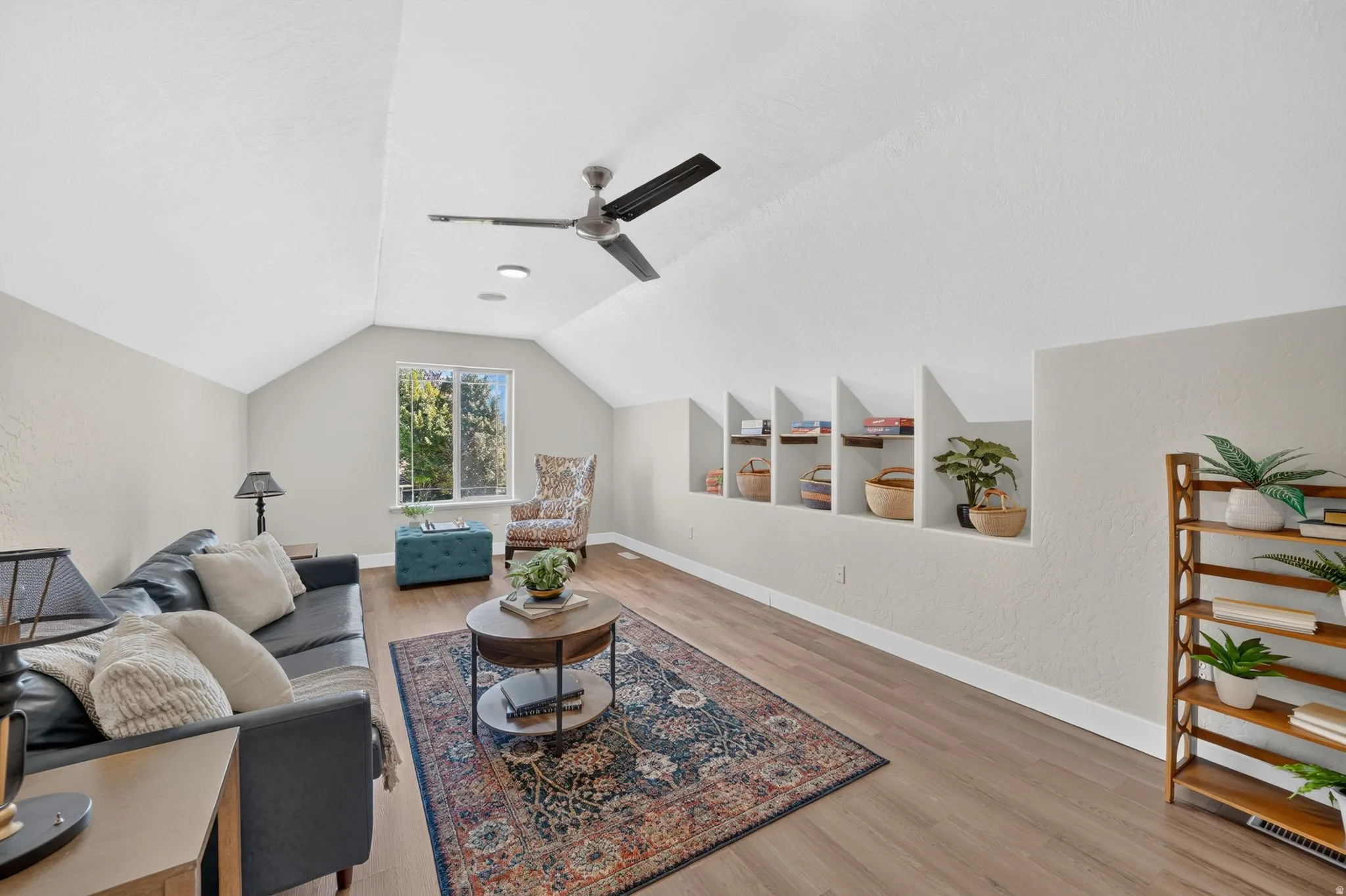 Vaulted ceiling featuring a ceiling fan, recessed lighting, wood-finish flooring, built-in display niches, and a window providing natural illumination