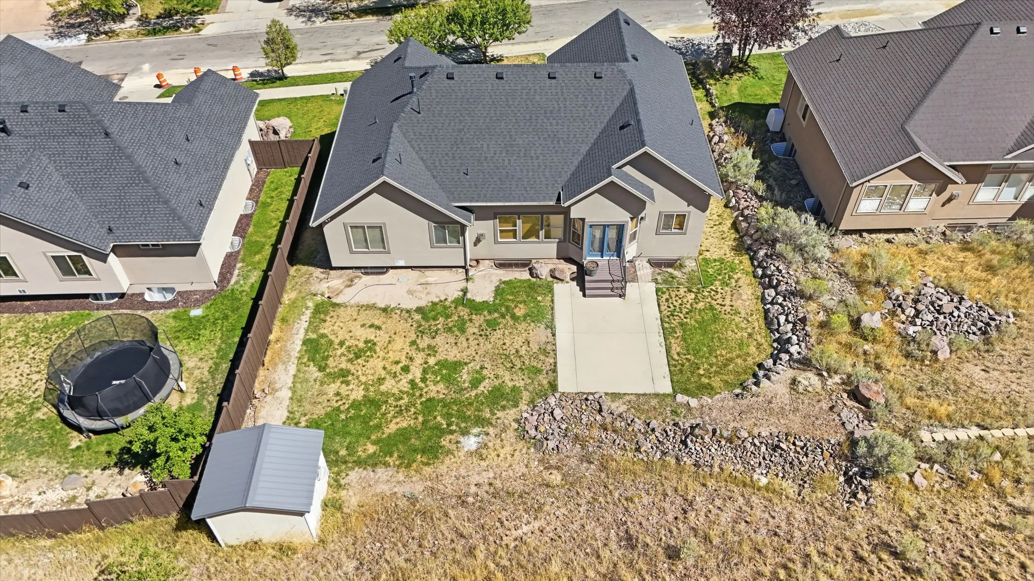 Rear exterior featuring a concrete patio, sloped yard, and mature vegetation