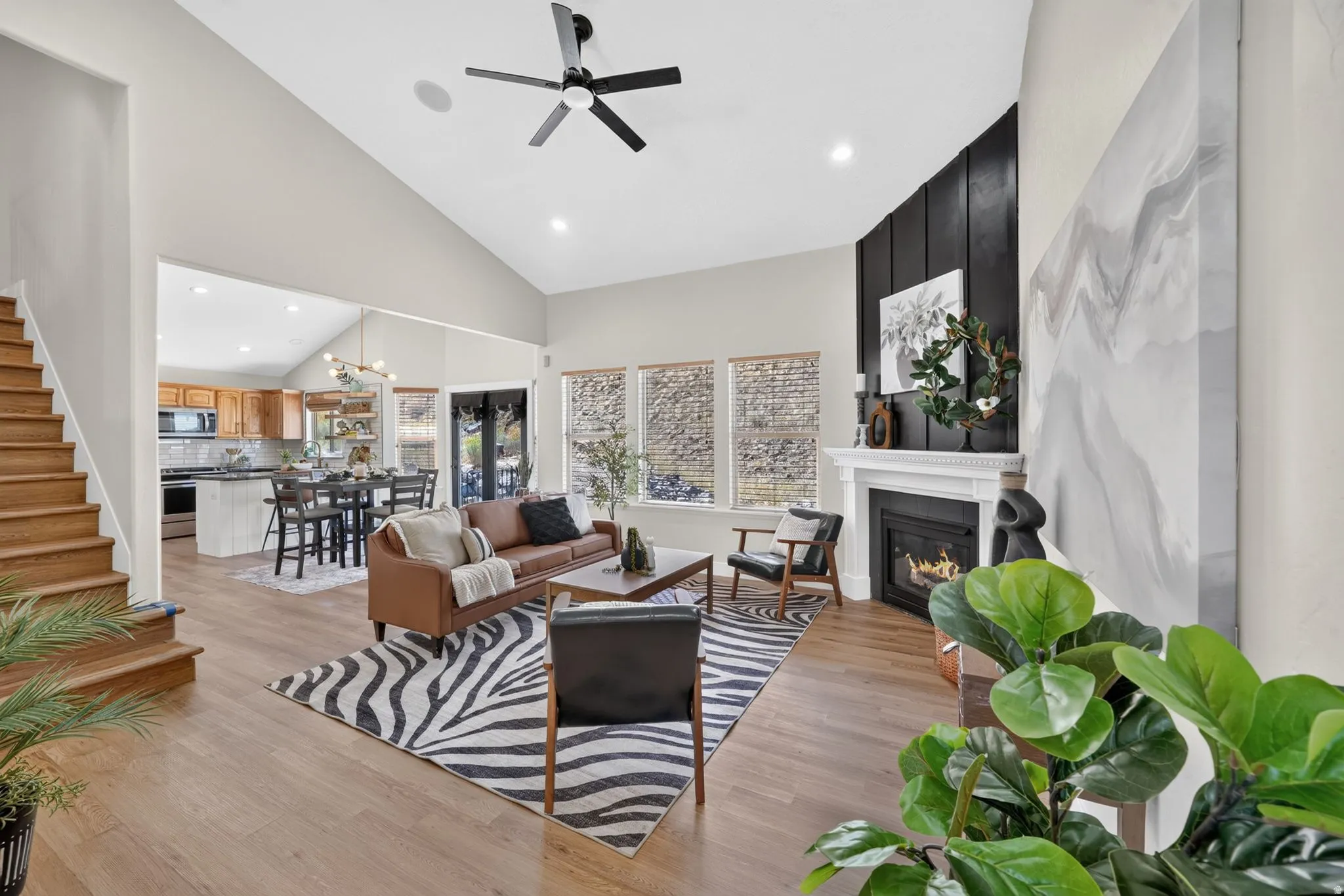 Open-concept living space featuring hardwood flooring, a gas fireplace with marble surround, recessed ceiling lighting, and a ceiling fan