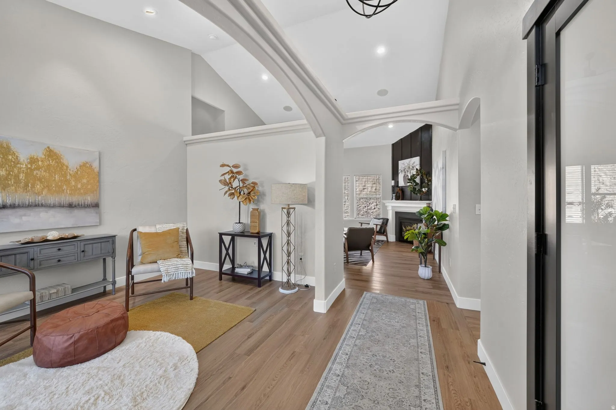 Vaulted ceilings with recessed lighting, wood-finish flooring, and arched doorways define this interior
