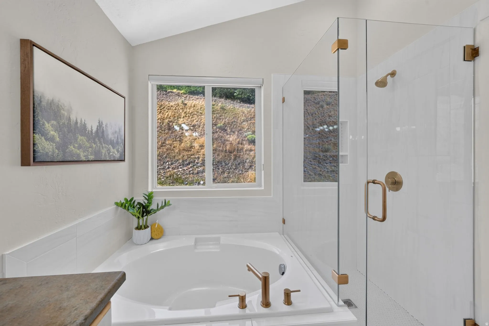 Soaking tub with bronze-finish fixtures, white tile surround, and a clear glass walk-in shower