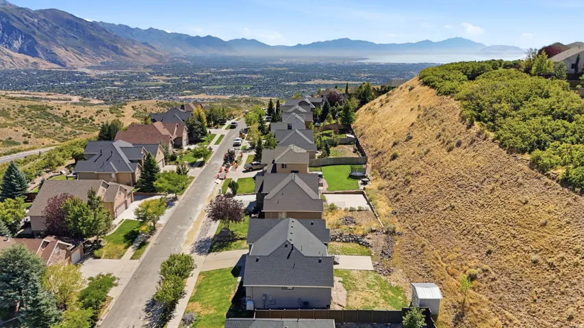 Aerial perspective highlighting a residential street with single-family homes, mountain backdrop, and distant cityscape