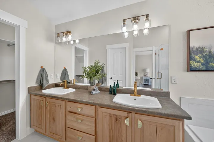 Dual vanity with light wood cabinetry, gold-finish hardware, and a durable countertop