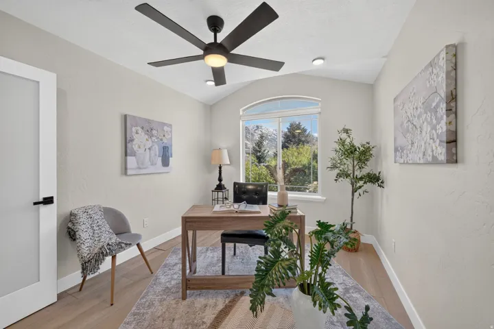 Vaulted ceiling with recessed lighting and a ceiling fan, arched window, and wood-finish flooring