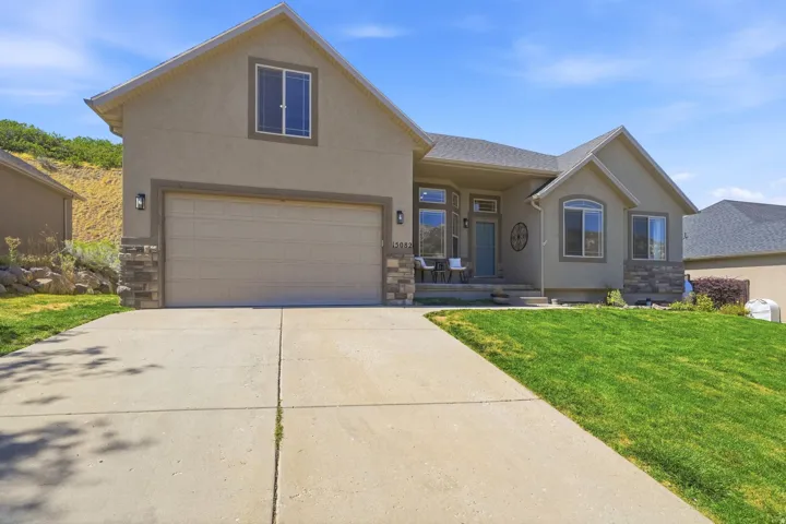 Contemporary stucco exterior featuring stone accents, a concrete driveway, and a covered front porch