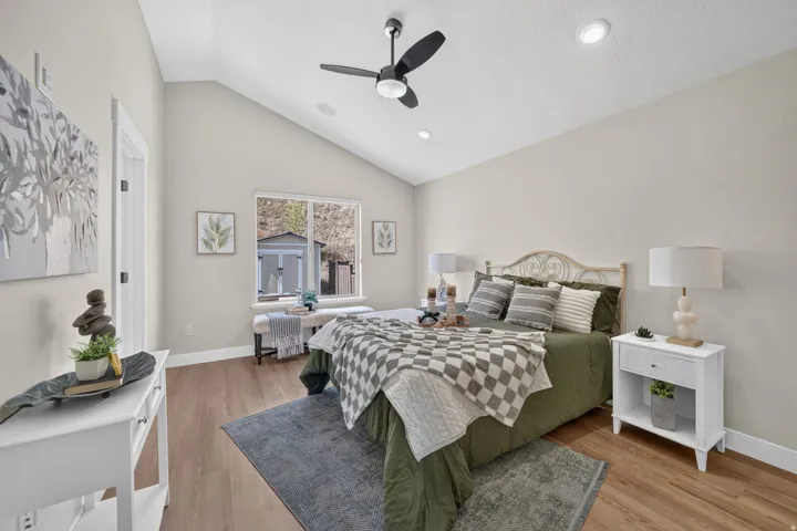 Vaulted ceiling with a ceiling fan, recessed lighting, wood-finish flooring, and a large window