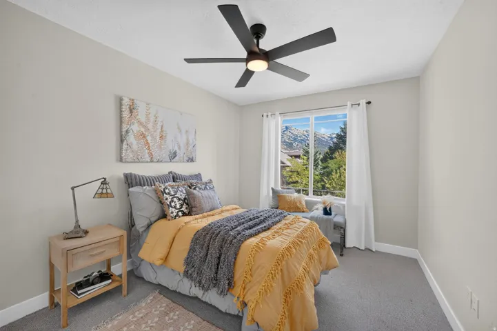 Recessed window with mountain and tree scenery, built-in window bench, ceiling fan with integrated lighting, and light-toned walls