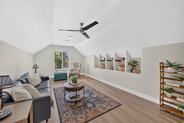 Vaulted ceiling featuring a ceiling fan, recessed lighting, wood-finish flooring, built-in display niches, and a window providing natural illumination