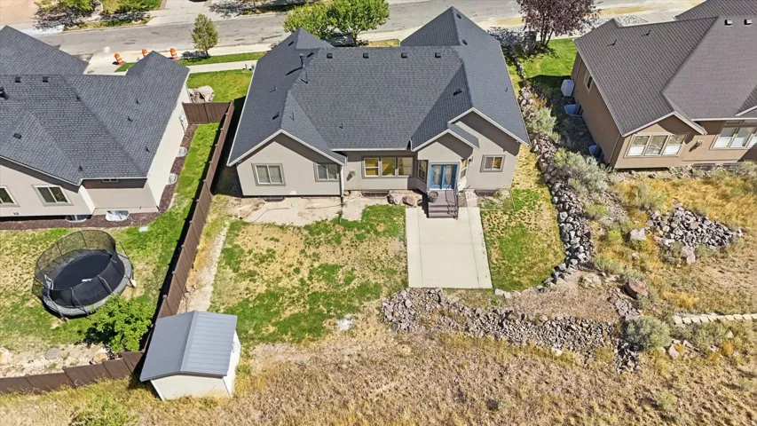 Rear exterior featuring a concrete patio, sloped yard, and mature vegetation