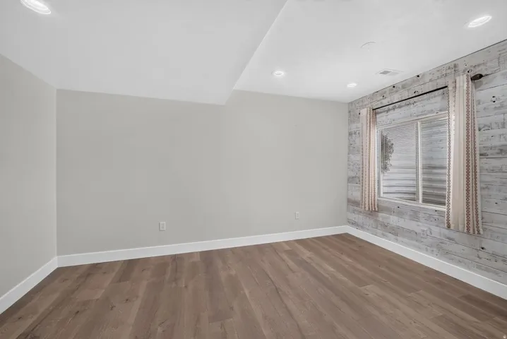 Wood-finish flooring, recessed lighting, and a window with a decorative wood-panel wall