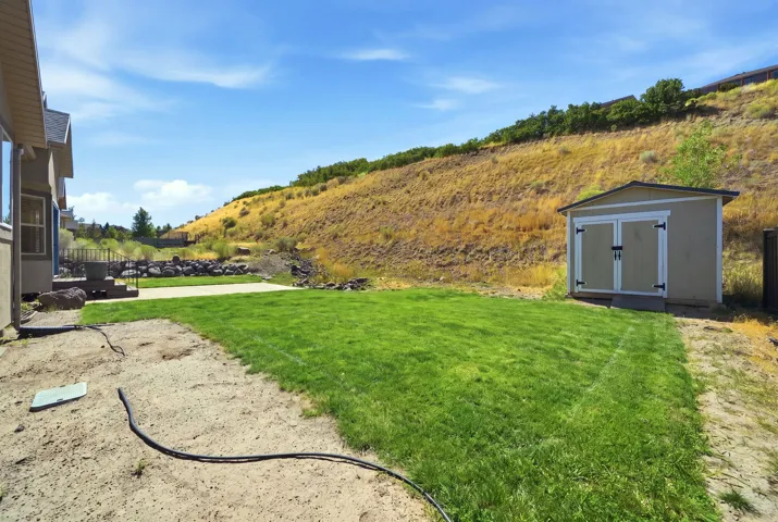Expansive exterior with a manicured lawn, concrete patio, and storage shed
