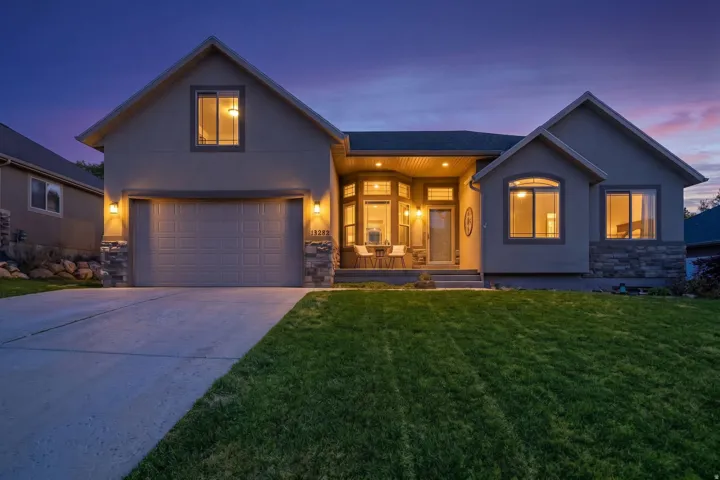 Stucco exterior with stone accents, a covered front porch, and an attached two-car garage