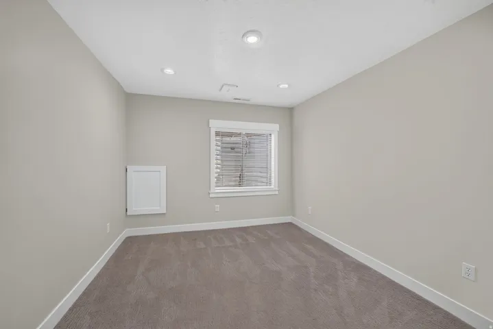 Recessed ceiling lighting, white trim, window with blinds, and neutral wall paint