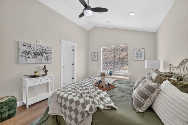 Vaulted ceiling with recessed lighting, wood-finish flooring, white paneled door, and a window with a built-in window seat