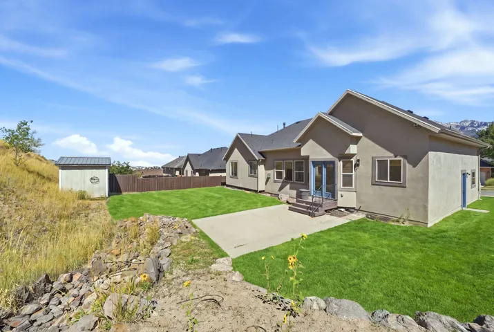 Manicured lawn with a concrete patio, wood-toned privacy fence, and a storage shed