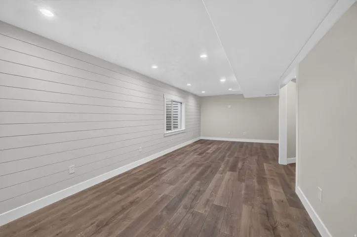 Wood-finish flooring, recessed lighting, horizontal paneling accent wall, window with blinds
