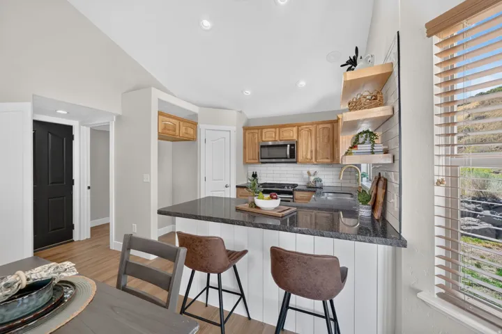 Kitchen featuring wood-finish cabinetry, dark countertops, a subway tile backsplash, and stainless steel appliances