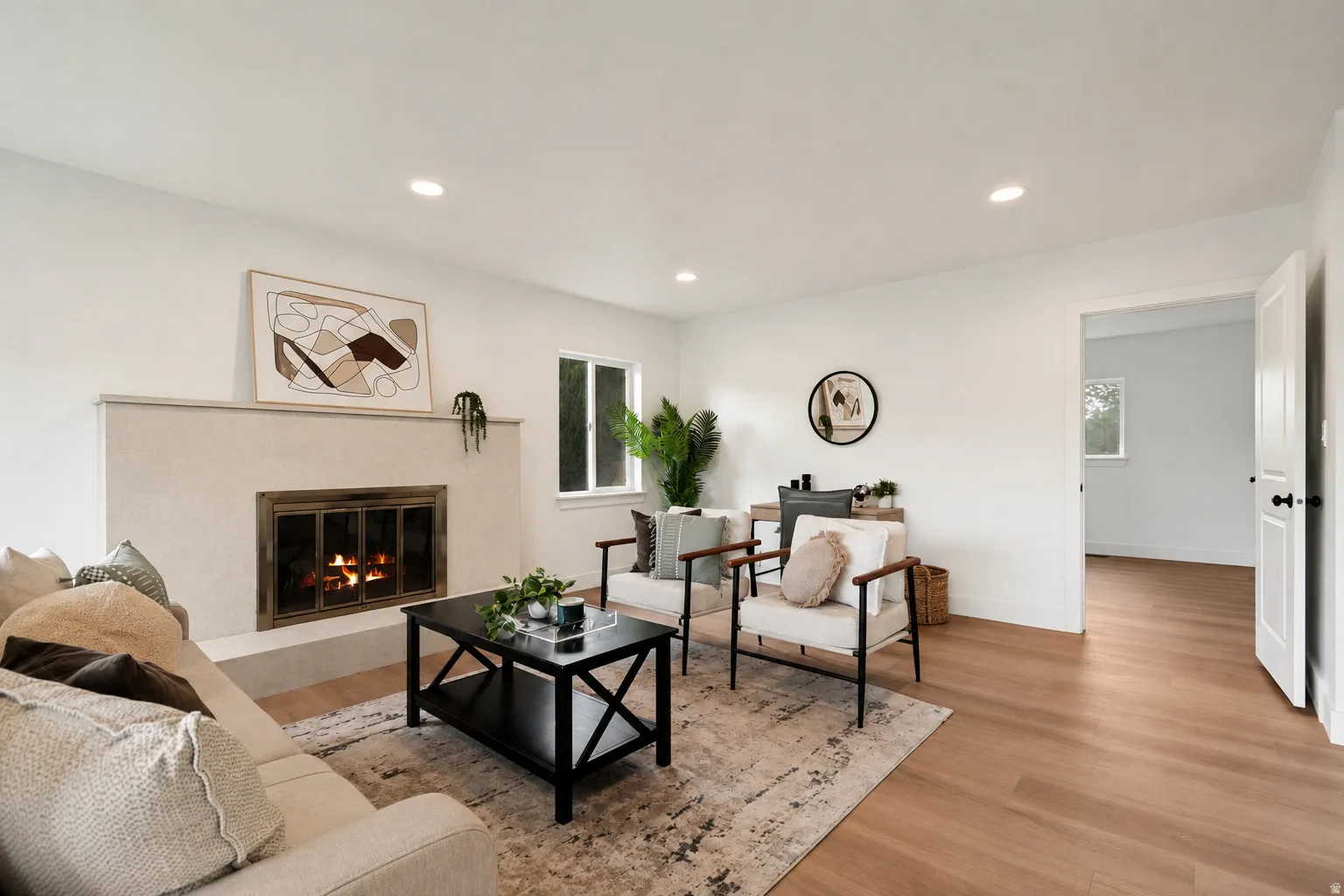 Recessed lighting, wood-finish flooring, white walls, built-in fireplace, and an open doorway