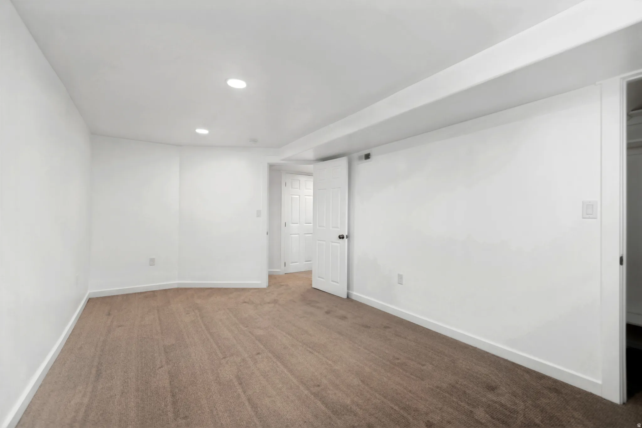 Recessed lighting, white walls, and neutral carpet flooring