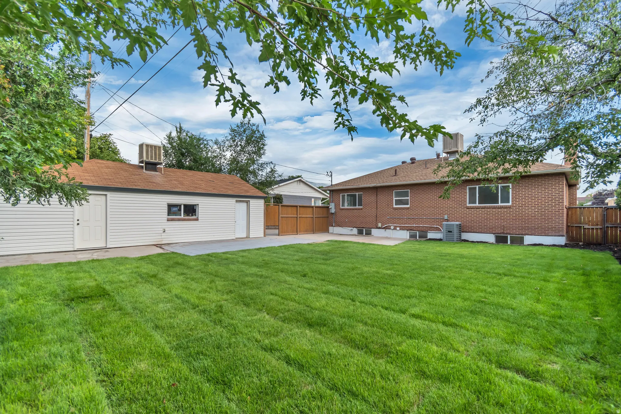 Expansive grassy yard with a detached garage, brick exterior, and wood fencing