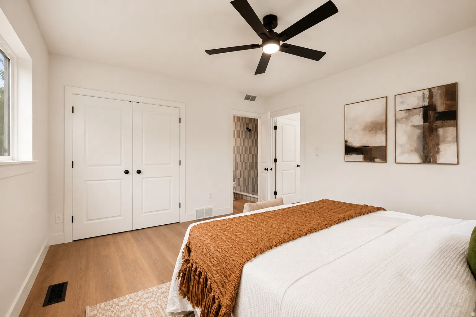 Wood-finish flooring, white walls, and a black ceiling fan