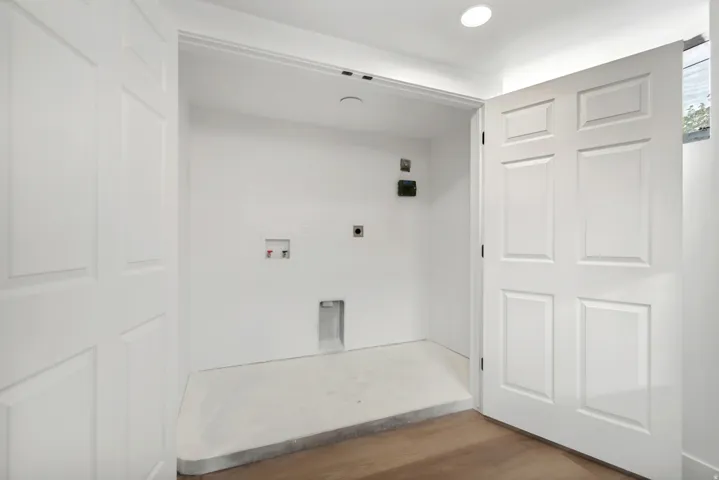 Utility closet with white paneled doors, recessed lighting, and wood-finish flooring