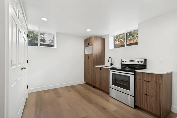 Wood-finish flooring, white walls, recessed lighting, wood cabinetry, and stainless steel appliances