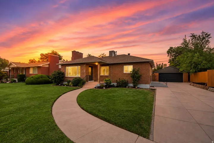 Brick exterior with a detached garage, concrete driveway, and a curved walkway