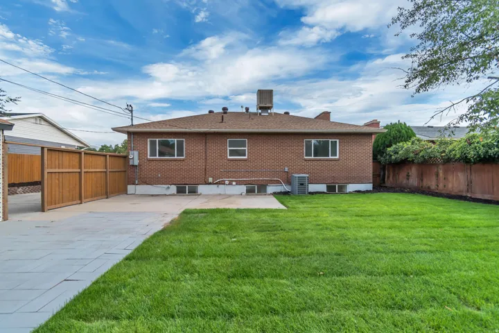 Expansive green lawn, brick exterior, paved patio area, and wood fencing