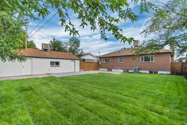 Expansive grassy yard with a detached garage, brick exterior, and wood fencing