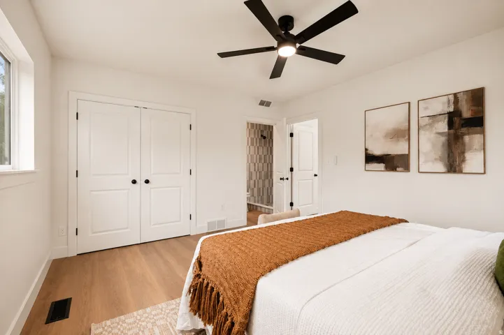 Wood-finish flooring, white walls, and a black ceiling fan