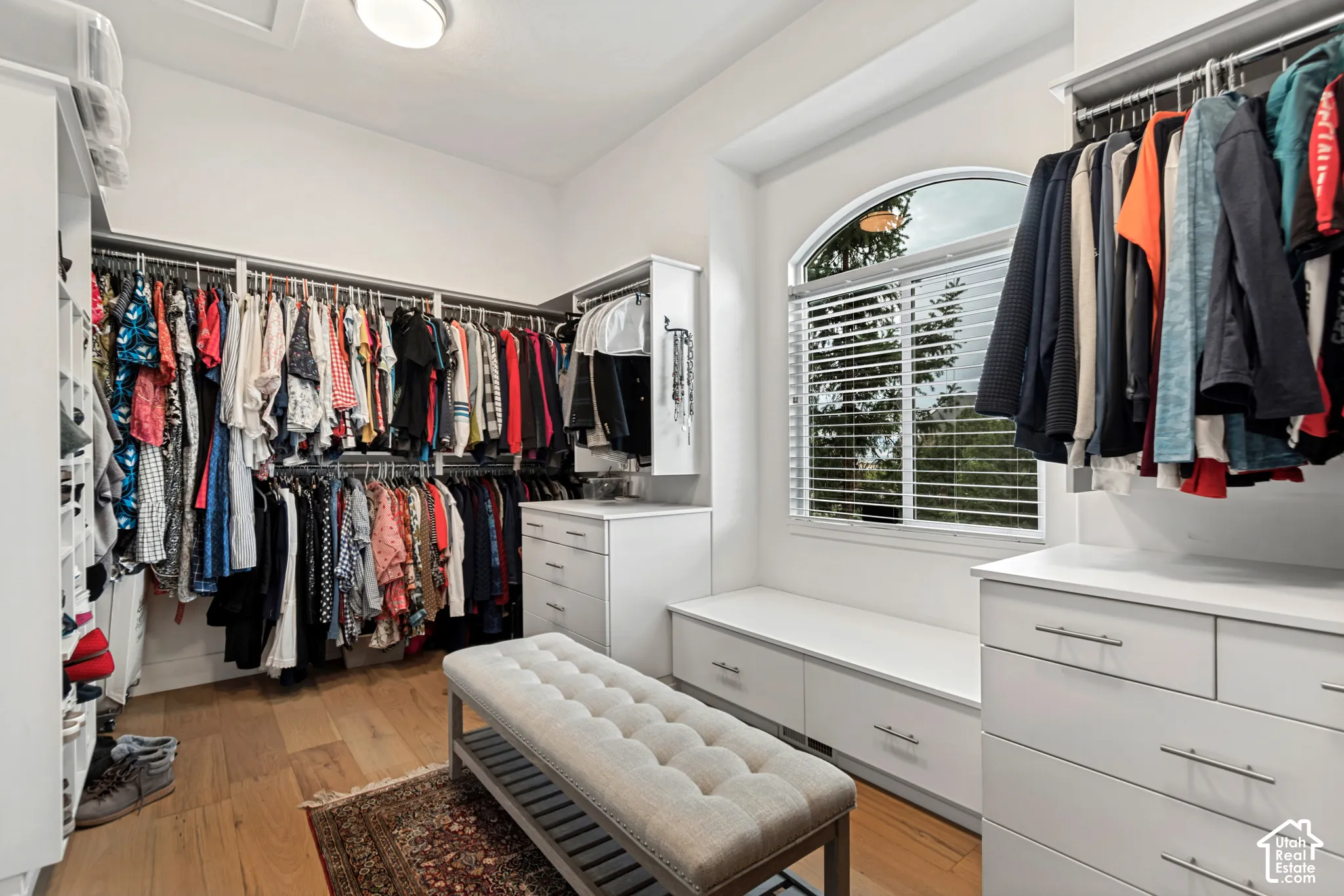 Custom closet system with extensive hanging storage and a built-in window bench